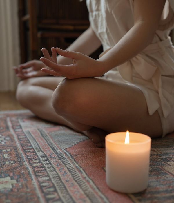 Woman in a calm yoga pose in a studio with warm ambient light.